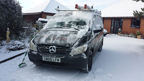Brushing snow off Scott Regan Chimney Sweeping van